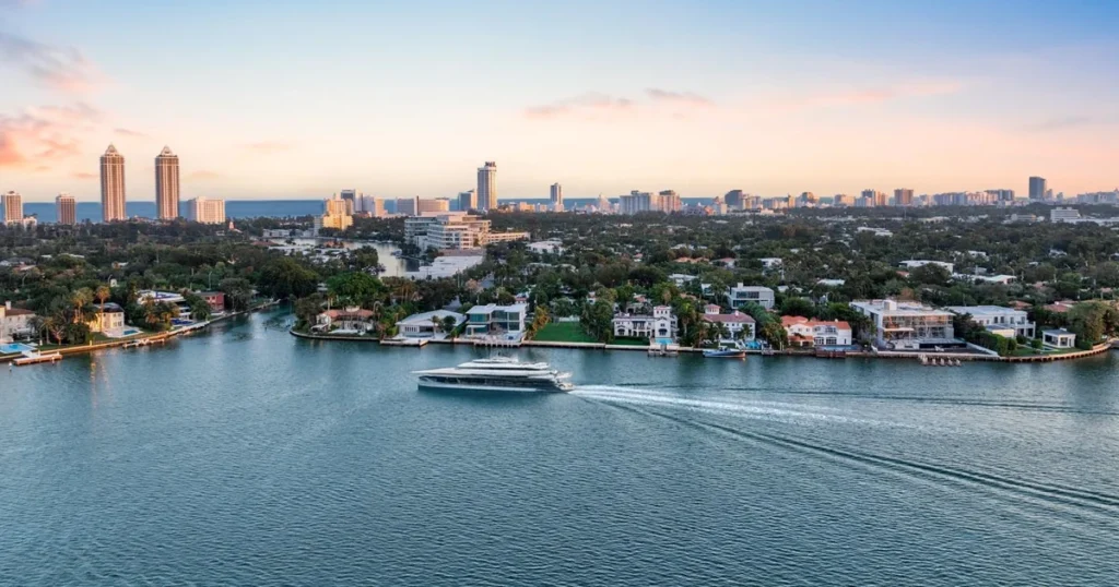 Luxury yacht cruising Biscayne Bay past North Bay Road waterfront mansions Miami Beach Billionaire's Row