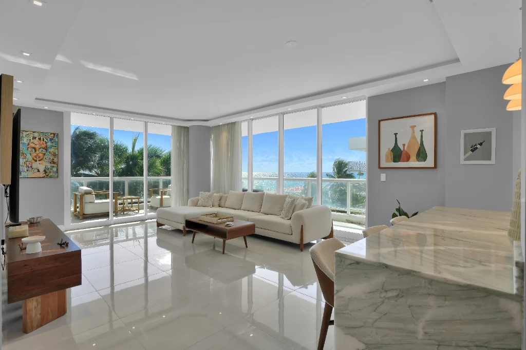 Interior of a luxury Miami Beach boutique condo living room featuring minimalist modern furniture, floor-to-ceiling windows, and a direct, unobstructed view of the Atlantic Ocean.